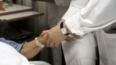 läkare håller patients hand
