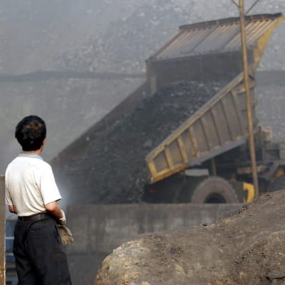 En kille tittar på när kol utvinns i Kina, bilden är tagen juli 2005.