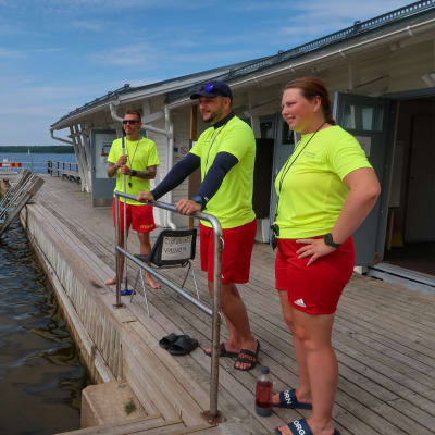 Bild av tre badvakter som står bredvid varandra på bryggan vid Simmis i Ekenäs. 