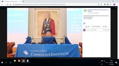 Xinning Song ser på en skärm som är draperad i blått tyg, bakom syns ett porträtt på universitetet