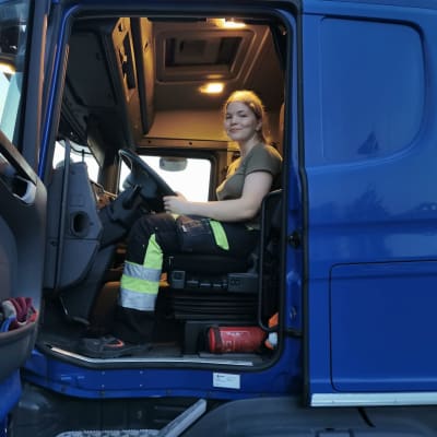 Henkilö istuu rekkaautossa kuskin paikalla.