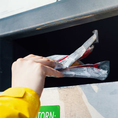 Ihminen laittaa roskan Rinki-ekopisteeseen. 