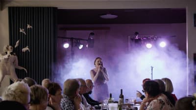 Kukka-yhtye esiintyy Varkauden klubilla dekkarifestivaalin iltatapahtumassa, ihmisiä pöytien ääressä.