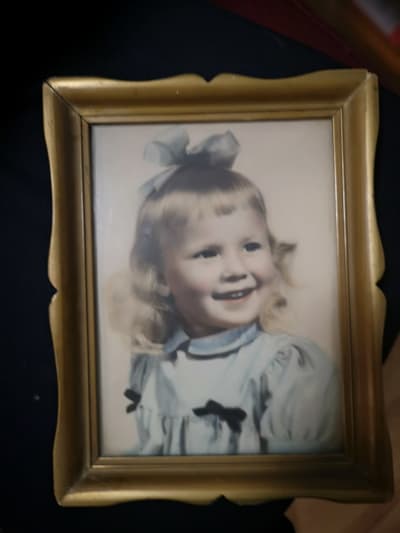 Kuva vanhasta muotokuvasta, jossa noin kaksivuotias tyttä kiharoissa hiuksissaan hymyilevänä.