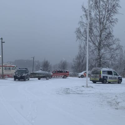 Lumisessa satamassa on poliisiauto, hälytysajoneuvoja ja merivartioston vene.