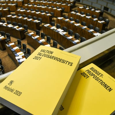Vuoden 2021 budjettikirja kuvattuna eduskunnan istuntosalissa.