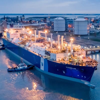 Ett stort fartyg vid en hamn intill fasinfrastruktur. På det blåa fartyget står det "Exemplar".