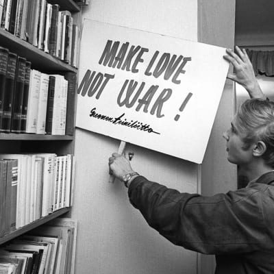 Erkki Tuomioja kädessään Teiniliiton banderolli "make love not war" 1968.