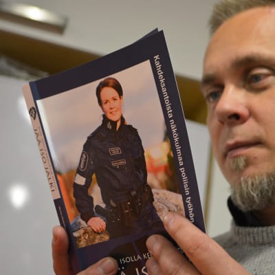 Poliisiviestinnän lehtori Marko Vesterbacka pitelee poliisiammattikorkeakoulun pääsykoekirjaa.