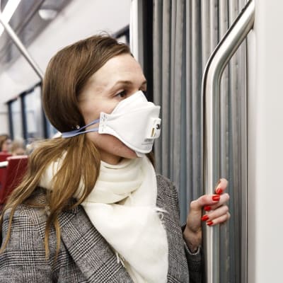 En kvinna bär munskydd i spårvagnen.
