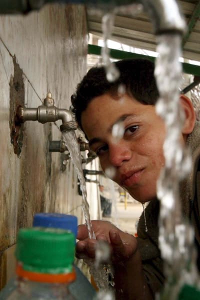 Palestinsk pojke fyller vattenkanistrar på flyktingläger i södra Gaza
