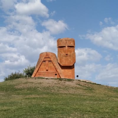 En skulptur föreställande en stiliserad man och kvinna uppe på en kulle.