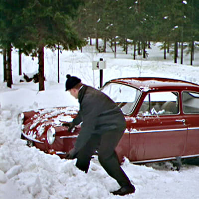 Mies lapioi autoa lumesta valistusfilmissä Turvallista talviajoa (1966)