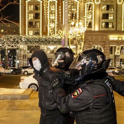 Mellakkavarusteisiin pukeutuneet poliisit taluttavat mielenosoittajaa Moskovassa.