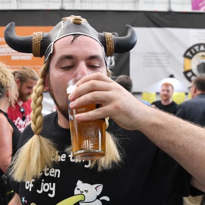 Sarvihattuinen mies juo olutta olutfestivaaleilla Lontoossa.