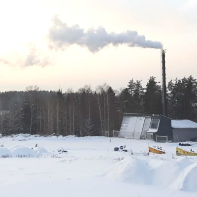 Ett värmeverk i vintrig miljö där det kommer ut rök ur skorstenen.