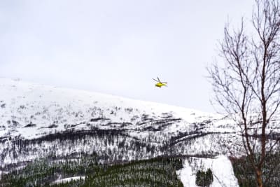 En helikopter flyger över snöklädda fjäll.