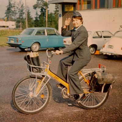 Naispostinkantaja lähdössä jakamaan postia polkupyörällä (1970-luku).