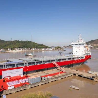 Rött fraktfartyg förtöjt vid pontoner, fartyget heter Lovisa.