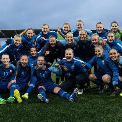 Suomen naisten jalkapallomaajoukkue nurmella iloiset ilmeet kasvoillaan.