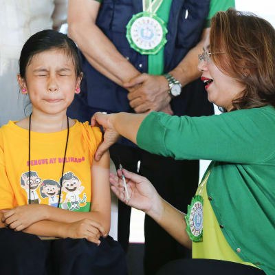 Entinen terveysministeri  Janette Garin antaa denguekuumerokotetta koululaiselle.