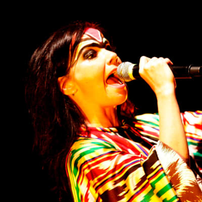 Björk sjunger i en mikrofon som hon håller i handen.