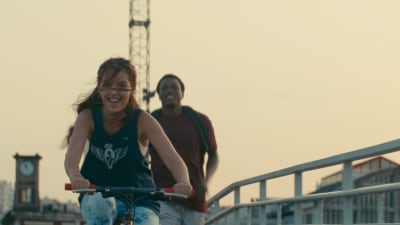 En flicka cyklar och en pojke springer bakom henne med blicken riktad mot kameran.