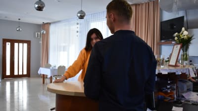 En kvinna talar med en man i en hotellreception.