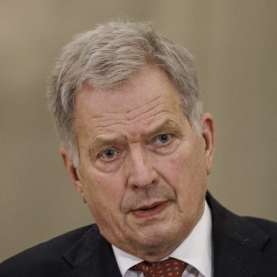 Sauli Niinistö sitter framför en räcka mikrofoner.