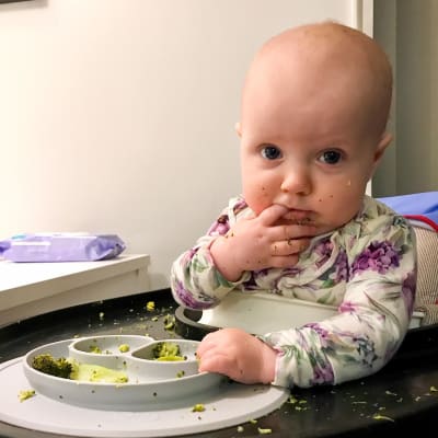 en ettåring äter broccoli med egna händer