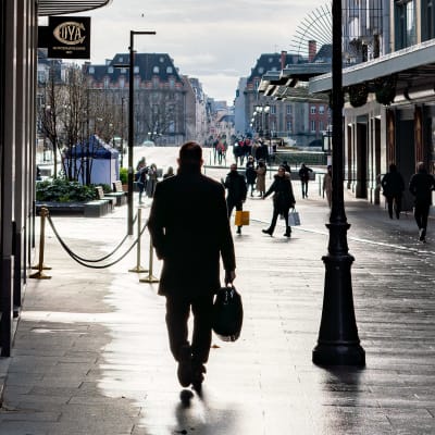 Mies kävelee kadulla Pariiisissa. Hän kantaa laukkua oikeassa kädessään. Taustalla näkyy muita ihmisiä.