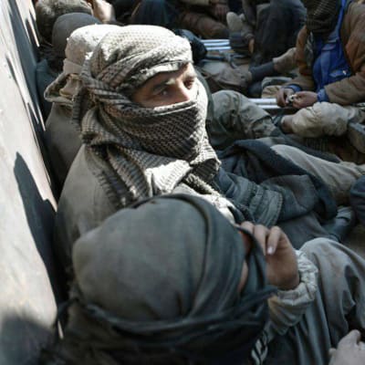 Män som lämnade IS sista fäste i Syrien och togs tillfånga sitter på ett lastbilsflak.