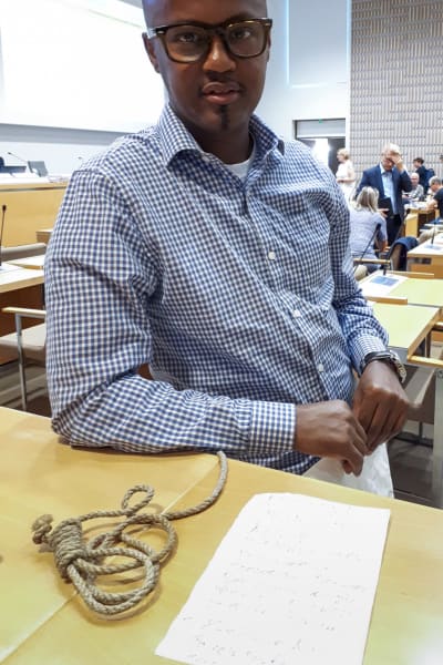 Abdirahim Hussein på bild med hängsnara och hotbrev som skickats till honom på Helsingfors stadsfullmäktige.