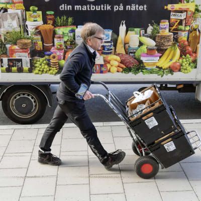 Ruokalähetti työntää ostoksia nokkakärryillä Tukholmassa.