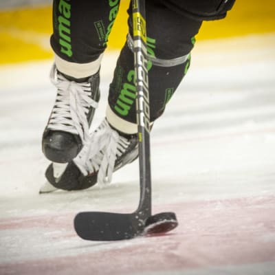En person på skridskor för en puck framåt med sin klubba.