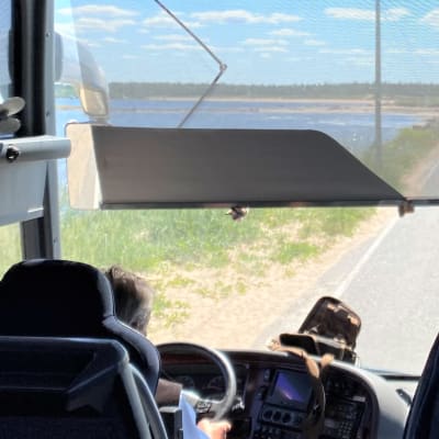 Mikko Kallioinen ajaa bussia Ohtakarin maisemissa Lohtajalla. Meri näkyy molemmin puolin tietä.