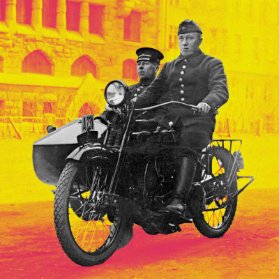 Palomies ja ruiskumestari ajavat Helsingin palolaitoksen sivuvaunullisella Harley-Davidson-moottoripyörän 1920-luvulla. Taustalla alipäällystön lapsia.