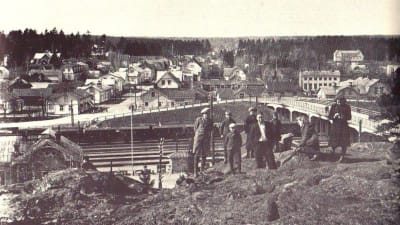 Bild från den gamla järnvägsbron 1941 i Karis. Människor sitter på berget framför bron.