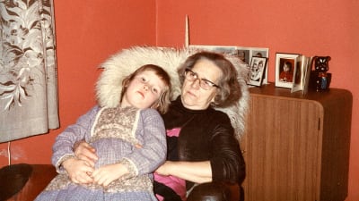 Kuvassa Merja Kyllönen lapsena istumassa hänelle rakkaan mummonsa Saara Materon sylissä 1980-luvun alkupuolella. 