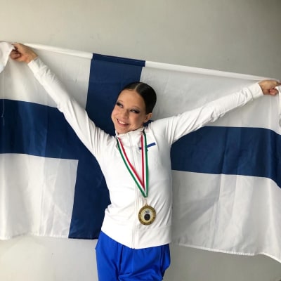 Tankotanssija Mandi Koskela pitelee suomenlippua kultamitali kaulassaan. 