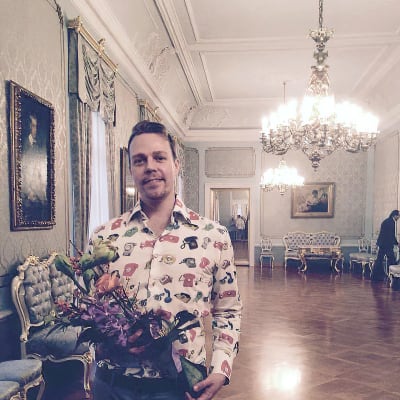 Tero Puha Smolnan salissa käsissään kukkakimppu. Taustalla salin koristeellinen ointeriööri.