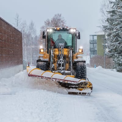 Iso auraustraktori poistaa lunta kadulta Jyväskylässä. 