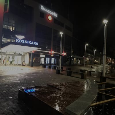 Kauppakeskus Koskikara Valkeakosken keskustassa illan pimeydessä, katuvalot valaiset tyhjää katua.