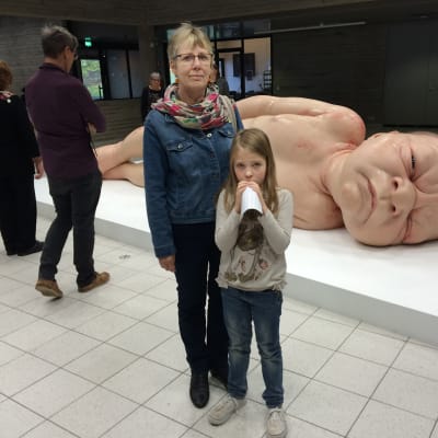 Nainen ja pikkutyttö vastasyntynyttä esittävän teoksen edessä Sara Hildénin taidemuseossa.
