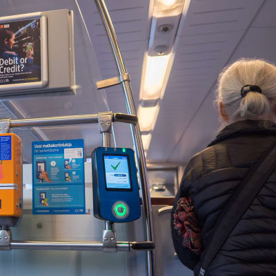Nainen luki matkakorttinsa astuessaan junaan.