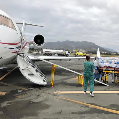 Sairaanhoitajat siirtävät potilasta lentokoneesta.