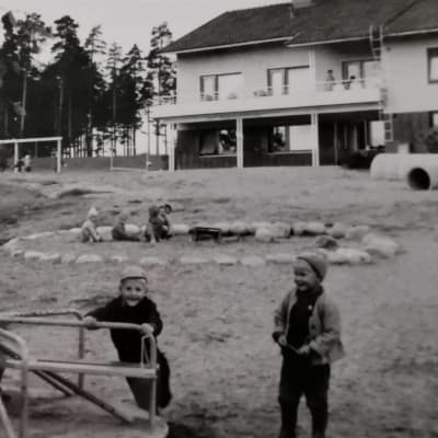 Lapset leikkivät Kärpäsen lastentalon pihalla karusellissa ja hiekkalaatikolla 1950-luvulla