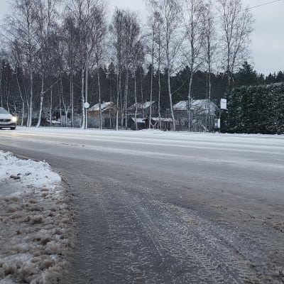 Lunta Littoistentiellä Turussa. Valkoinen auto ajaa kuvan vasemmalta laidalta kohti oikeaa. Taustalla omakotitalon pensasaita lumessa.
