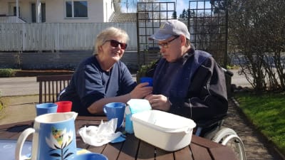 Eeva och Leif Lindell dricker kaffe ute på en solig terass. 