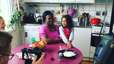 En kameraman filmar en mamma och ett barn i ett kök